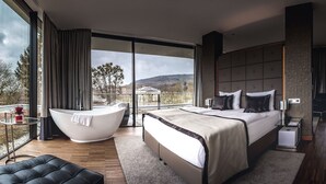 Un dormitorio moderno con una cama grande, una bañera y vistas al exterior.