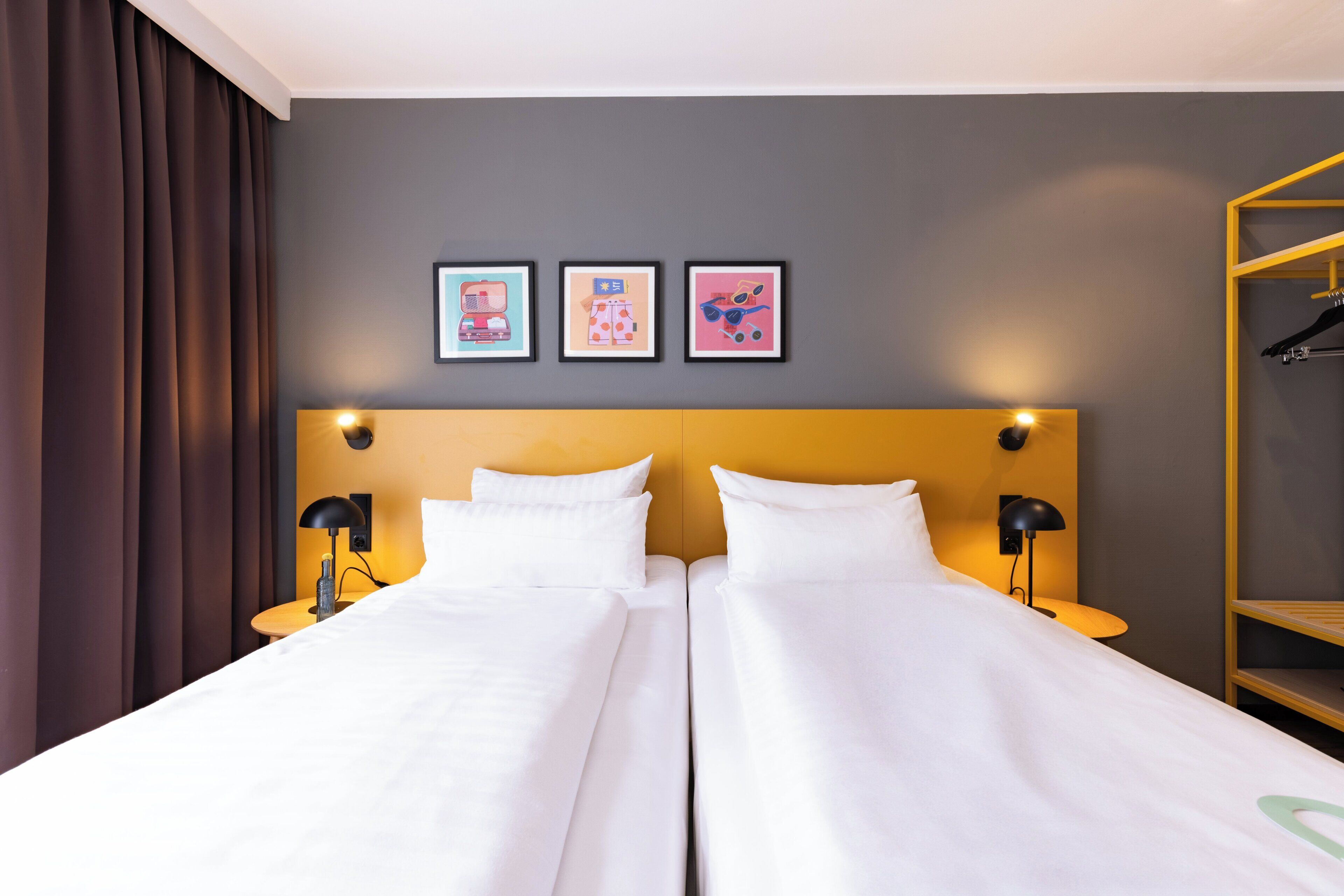 A hotel room with two beds, a wooden headboard, and a wardrobe with a yellow frame.