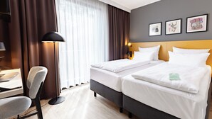 A hotel room with two beds, a desk, and a chair. - Garner Hotel Cologne East by IHG (Cologne)