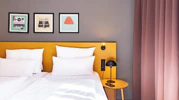 A hotel room with a bed, a bedside table with a lamp, and three framed pictures on the wall.