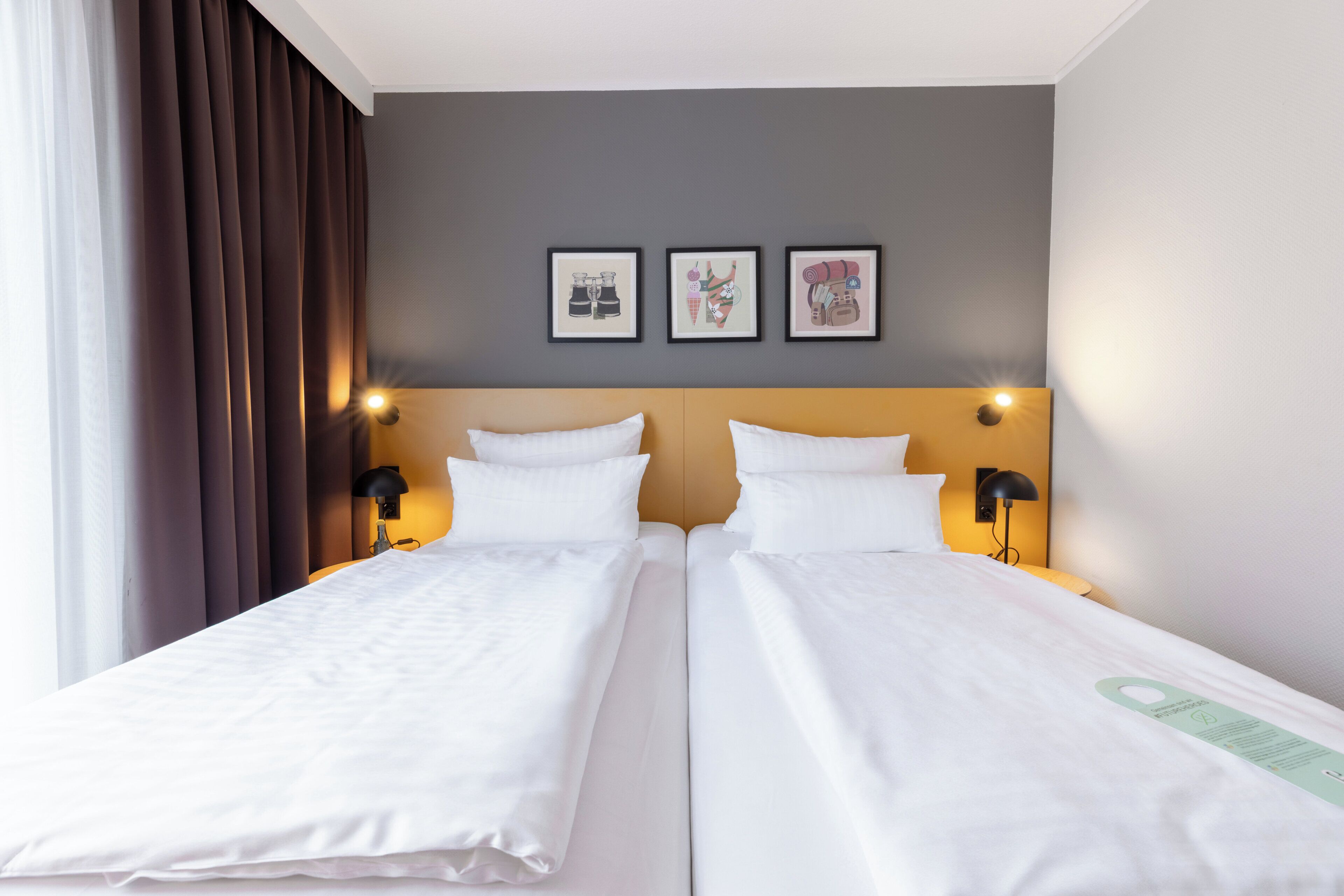 A double bed room with two bedside tables, a headboard, and three framed pictures on the wall.
