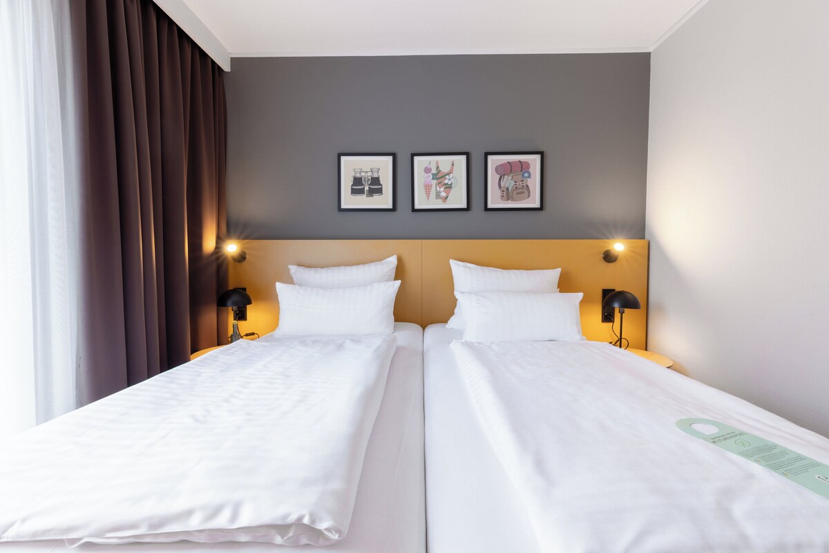 A double bed room with two bedside tables, a headboard, and three framed pictures on the wall.