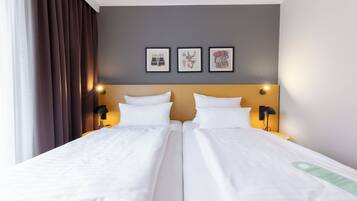 A double bed room with two bedside tables, a headboard, and three framed pictures on the wall.