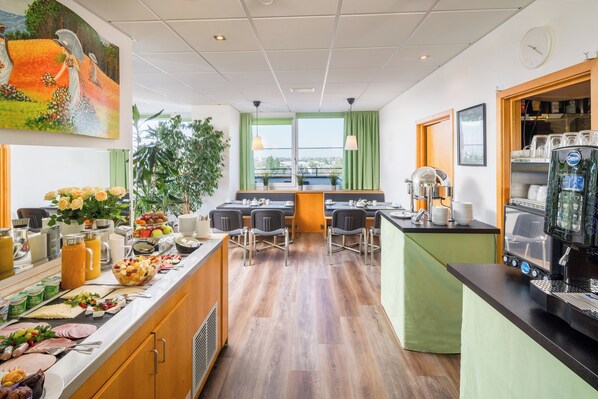 Un espace de restauration moderne dans un hôtel, comprenant un buffet, des tables et un coin café.