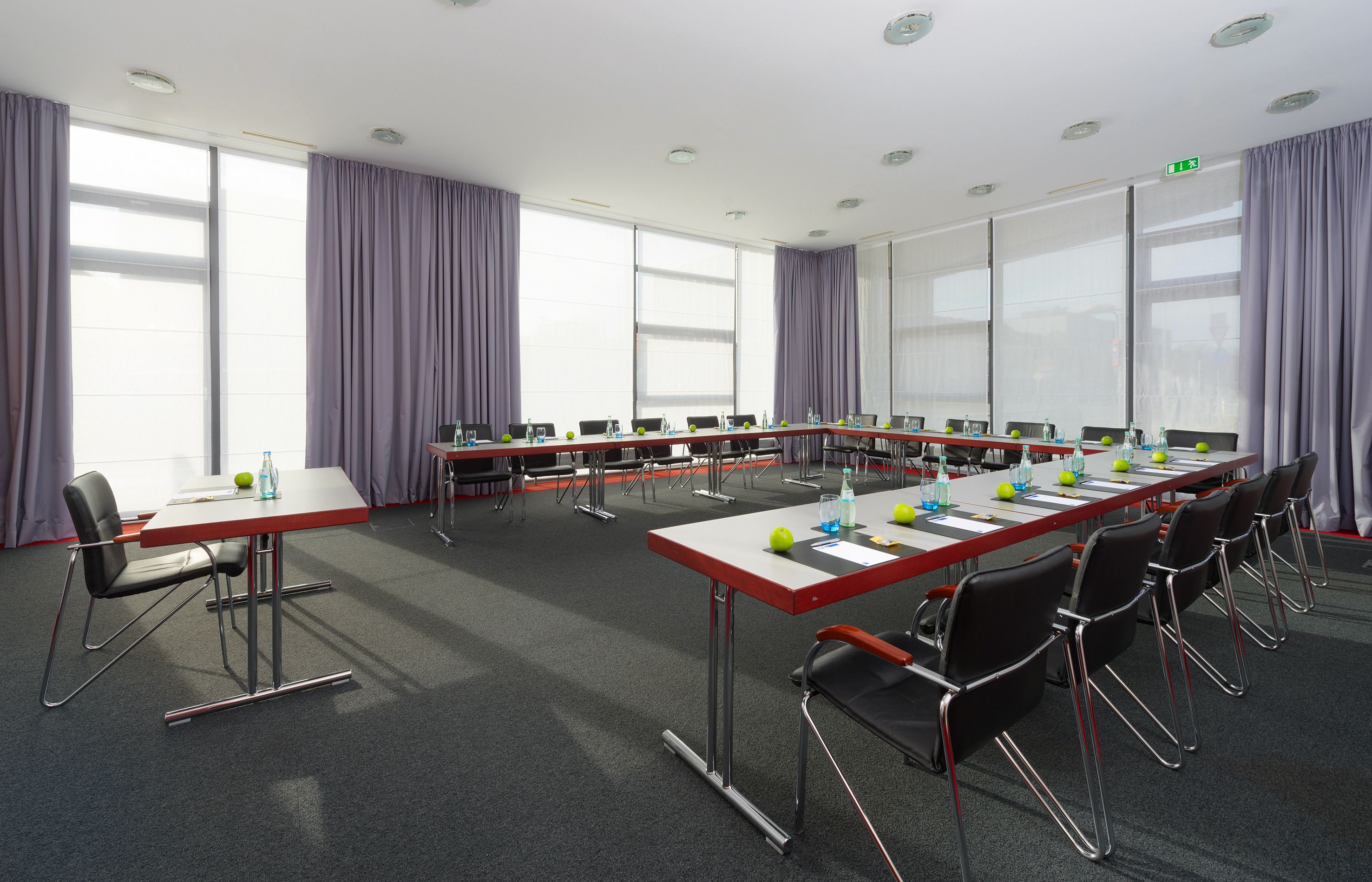 A conference room with a long table, chairs, and a projector screen.
