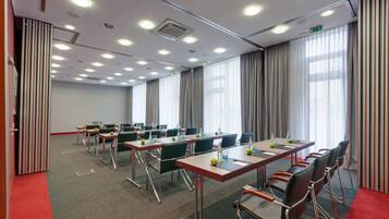 A conference room with multiple tables, chairs, and a red carpet.