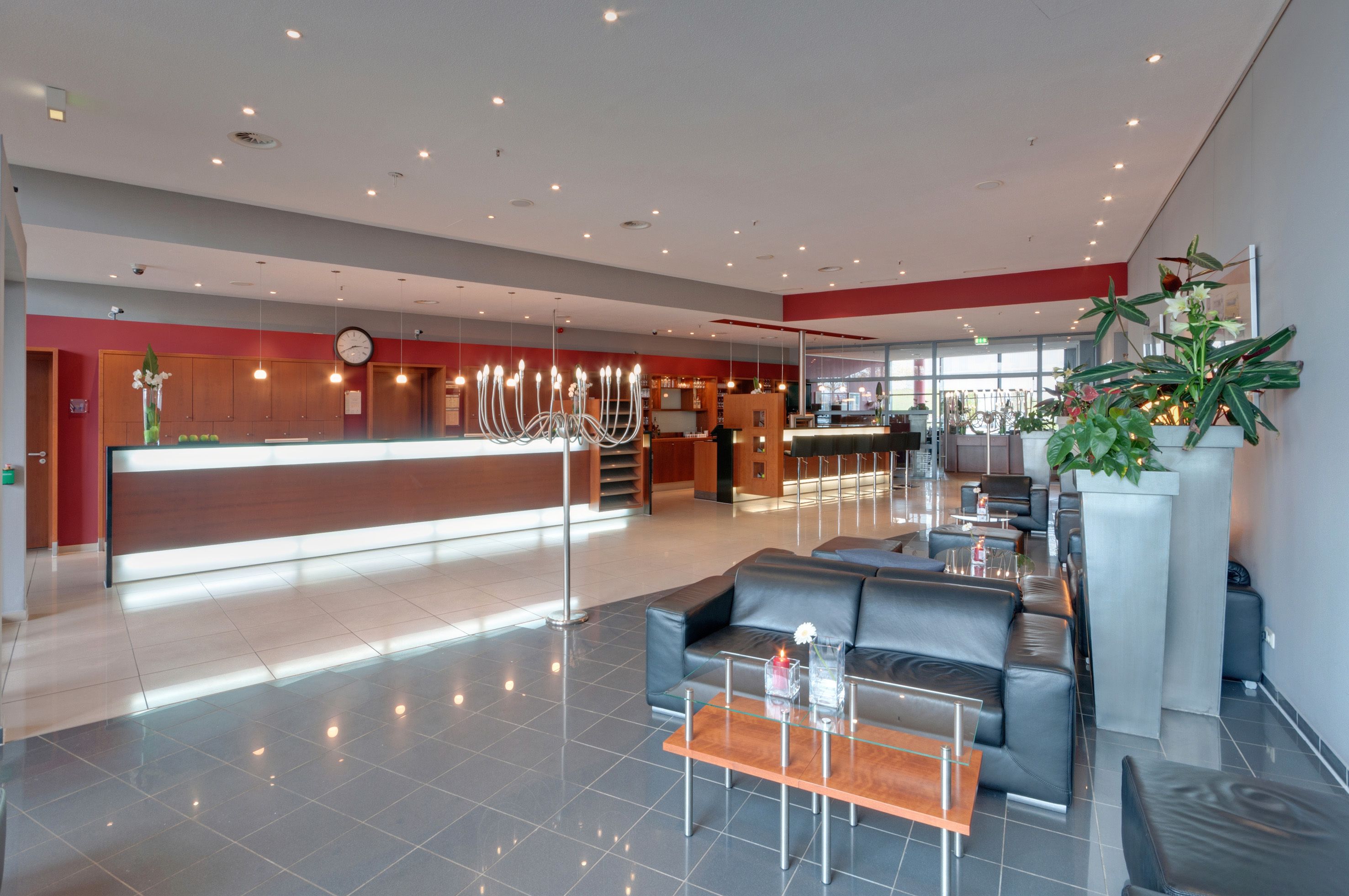 Un moderno vestíbulo de hotel con mostrador de recepción, asientos de cuero y una planta grande en maceta.
