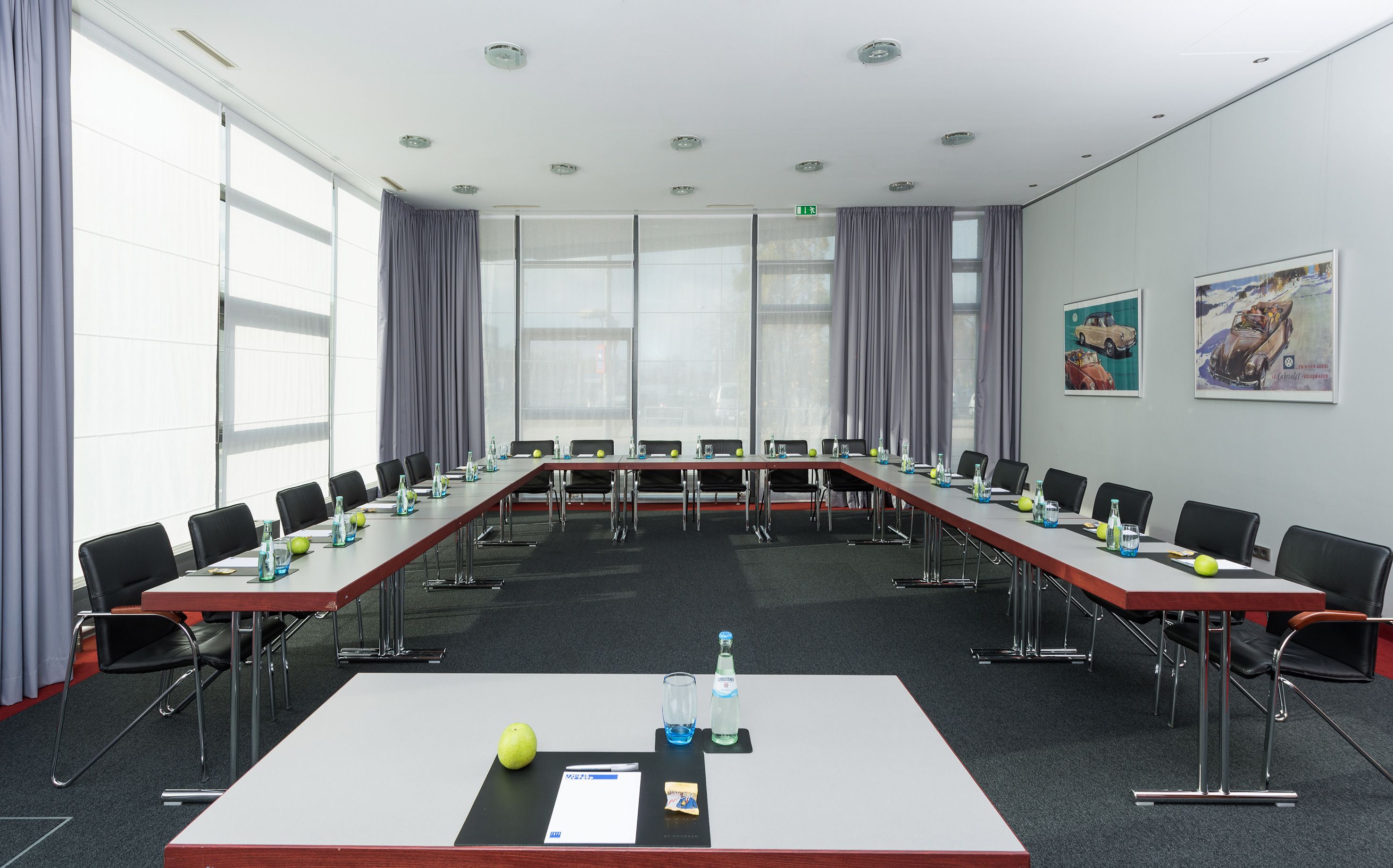 Un salón de conferencias con una larga mesa, sillas y una pantalla de proyector.