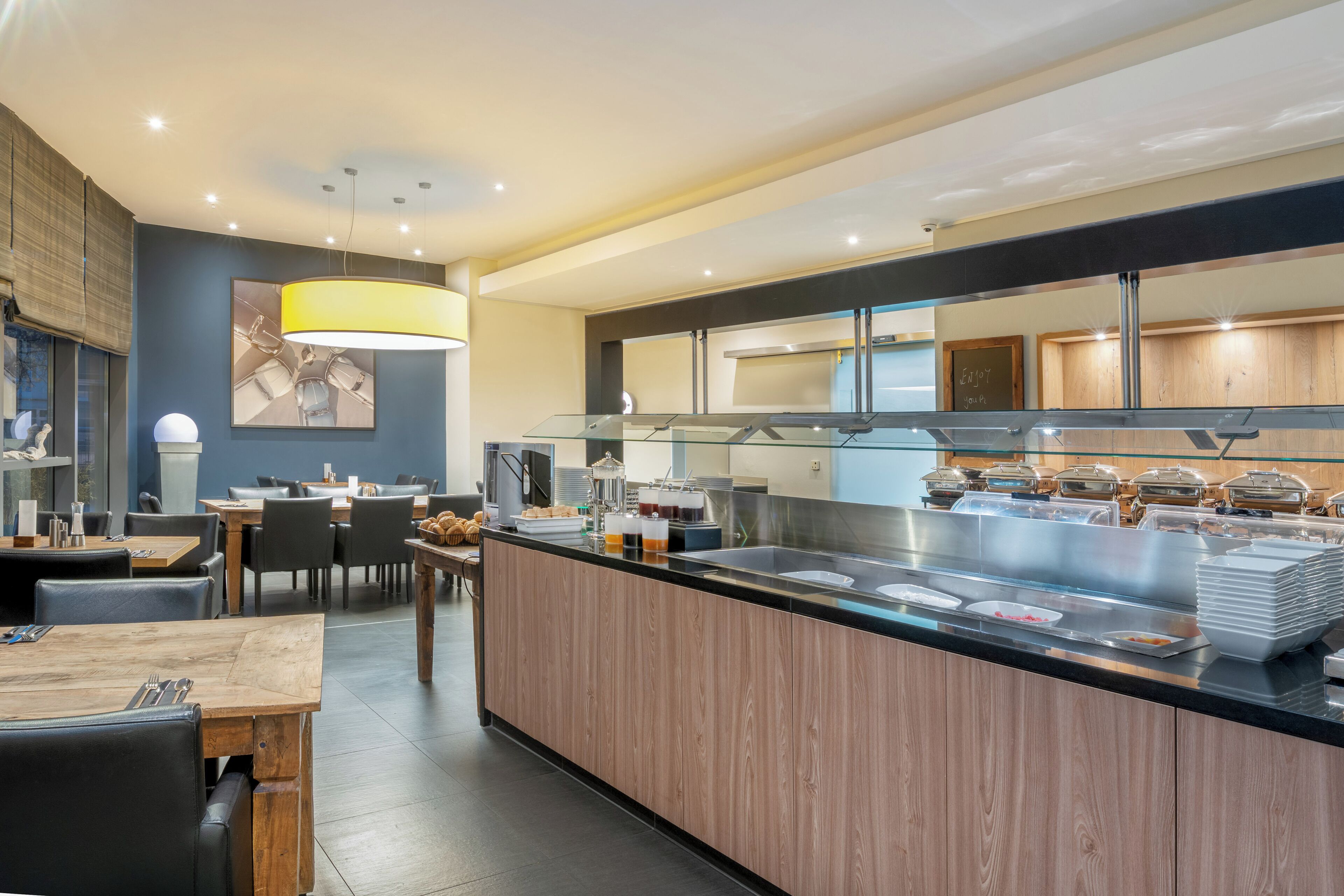 A modern restaurant with a central island, dining tables, and a buffet area.