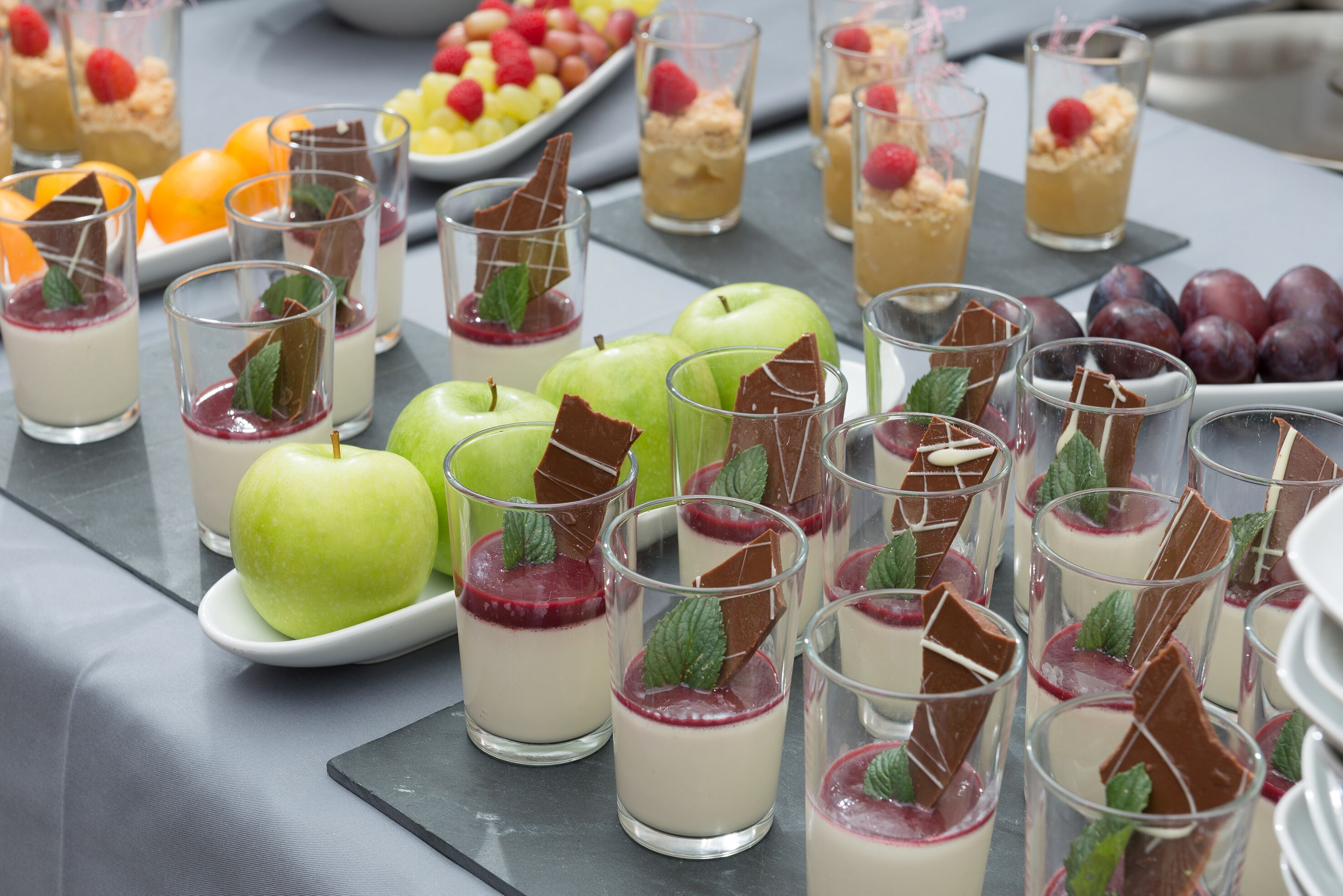Un assortiment de desserts comprenant des parfaits, des fruits et des morceaux de chocolat.