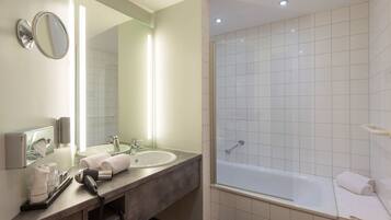 A modern bathroom with a double sink, a large mirror, a hairdryer, and a glass-enclosed shower area.