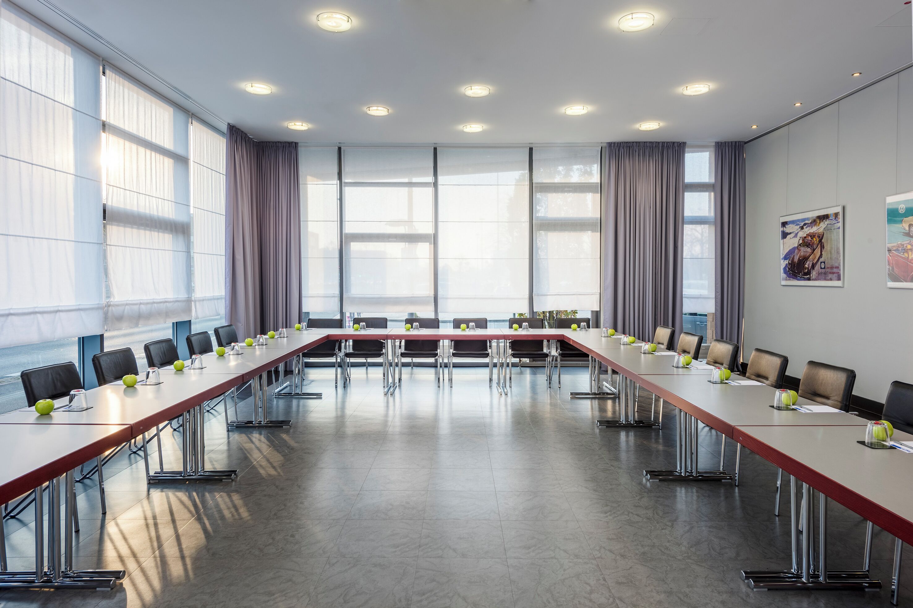 A conference room with a long table, chairs, and a large window with curtains.