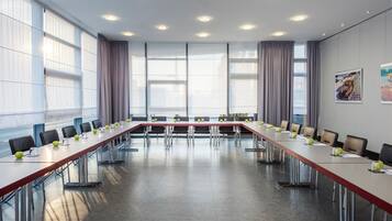 A conference room with a long table, chairs, and a large window with curtains.