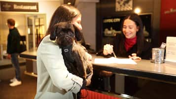 Una persona sosteniendo un perro pequeño en un mostrador, con un letrero que dice 'Restaurant'.