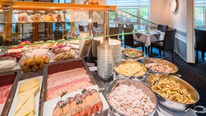 Un bufé con diversas opciones de comida, incluyendo carnes, quesos y ensaladas.