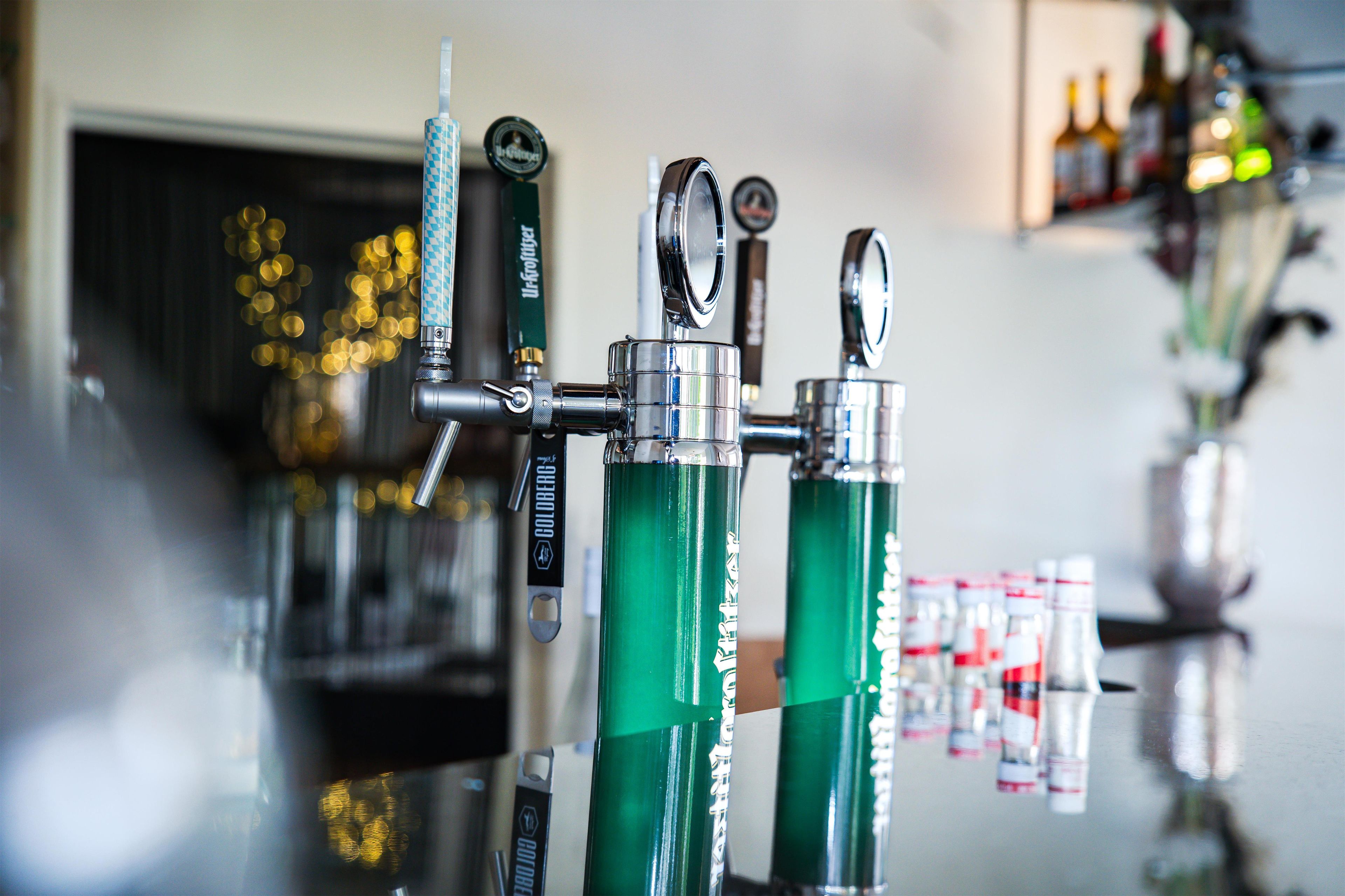 A bar with multiple taps and bottles in the background.