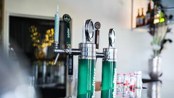 Un bar con varias llaves de cerveza y botellas al fondo.
