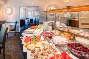 Een buffetgedeelte met diverse eetopties, zoals fruit, desserts en drankjes.