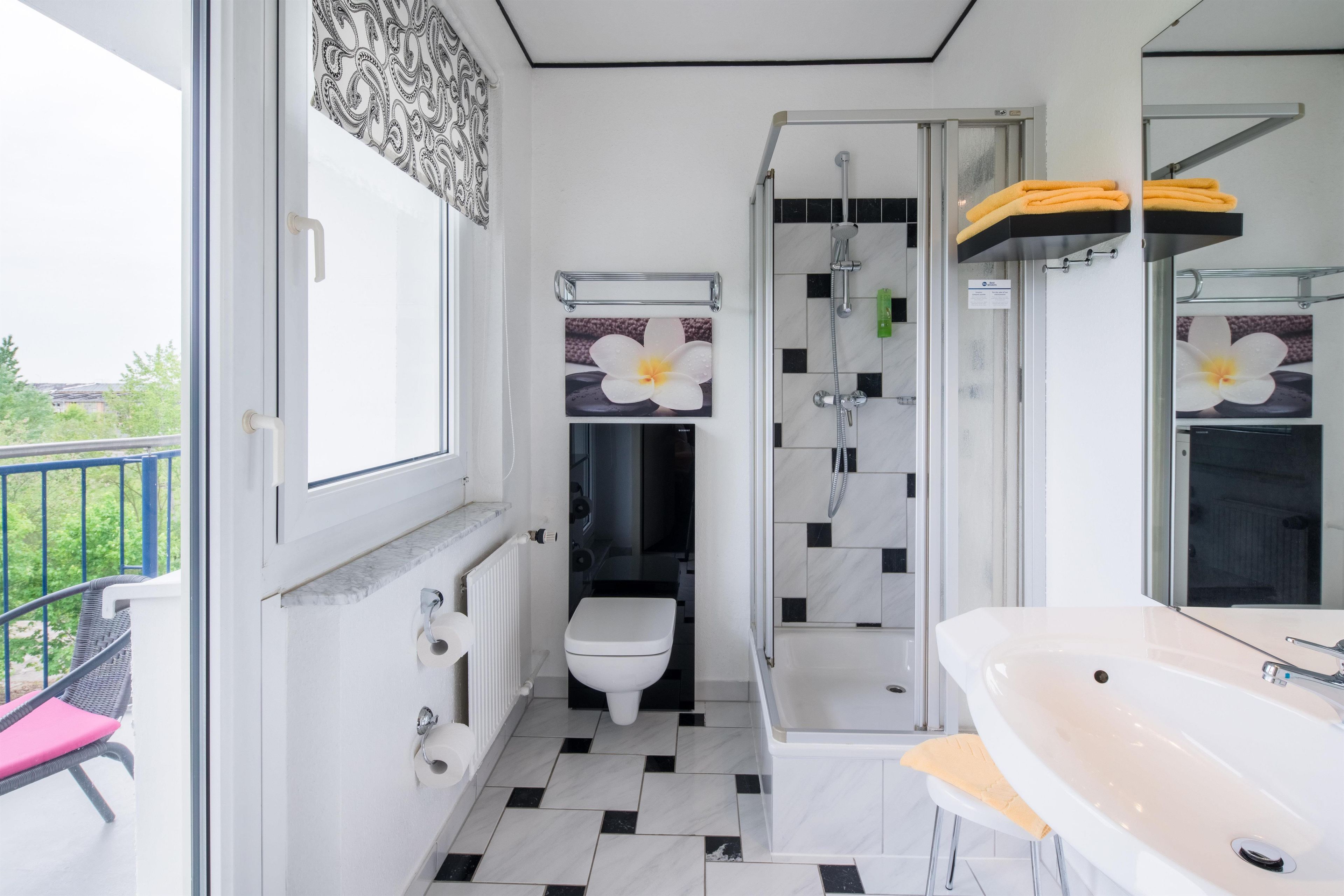 A bathroom with a toilet, shower, and sink.
