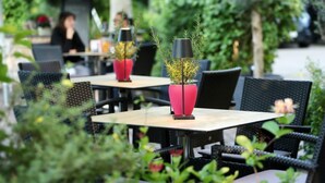 An outdoor seating area with tables and chairs, some with potted plants. - Best Western Hotel Windorf (Leipzig)