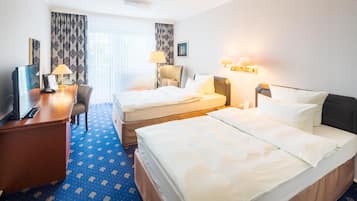 Habitación de hotel con dos camas, un escritorio, una silla, un televisor y una ventana con cortinas.