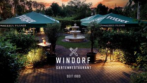 A garden restaurant with outdoor seating, a central fountain, and green umbrellas labeled "Feinherbes Pilsner". - Best Western Hotel Windorf (Leipzig)