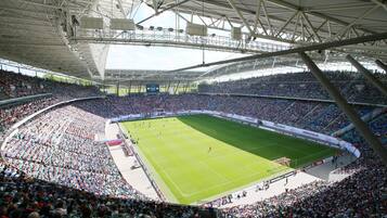 Ein großes Stadion mit mehreren Sitzebenen, einem zentralen Spielfeld und einem überdachten Oberteil.
