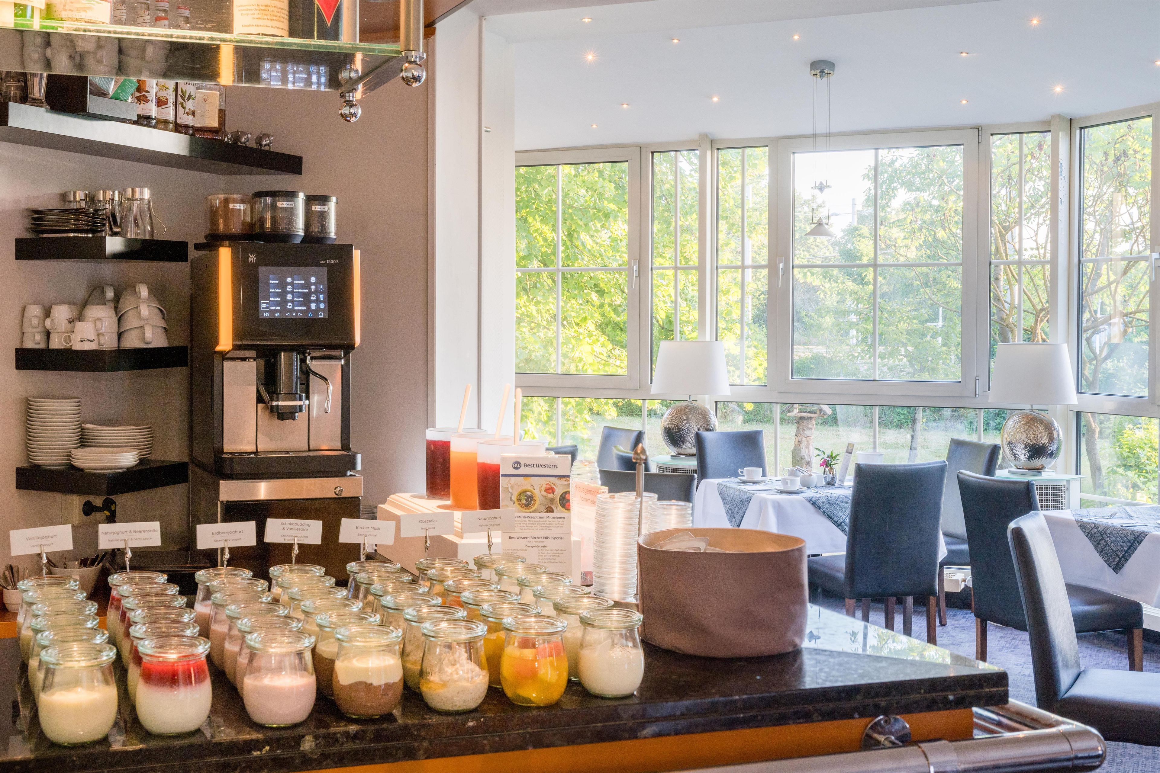 A café with a coffee machine, a variety of food items, and a seating area with tables and chairs.