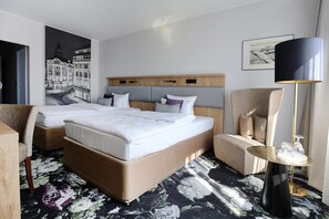 A hotel room with a large bed, two bedside tables, a chair, a desk, a lamp, and a painting on the wall.