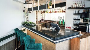A modern bar area with a granite countertop, bar stools, and a variety of bottles and glasses on shelves. - Best Western Hotel Windorf (Leipzig)