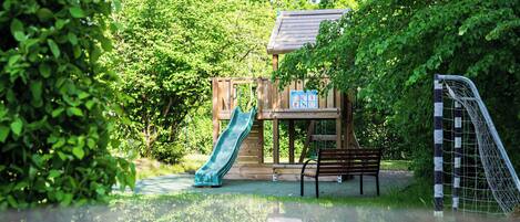 A playground with a slide, a bench, and a soccer goal.