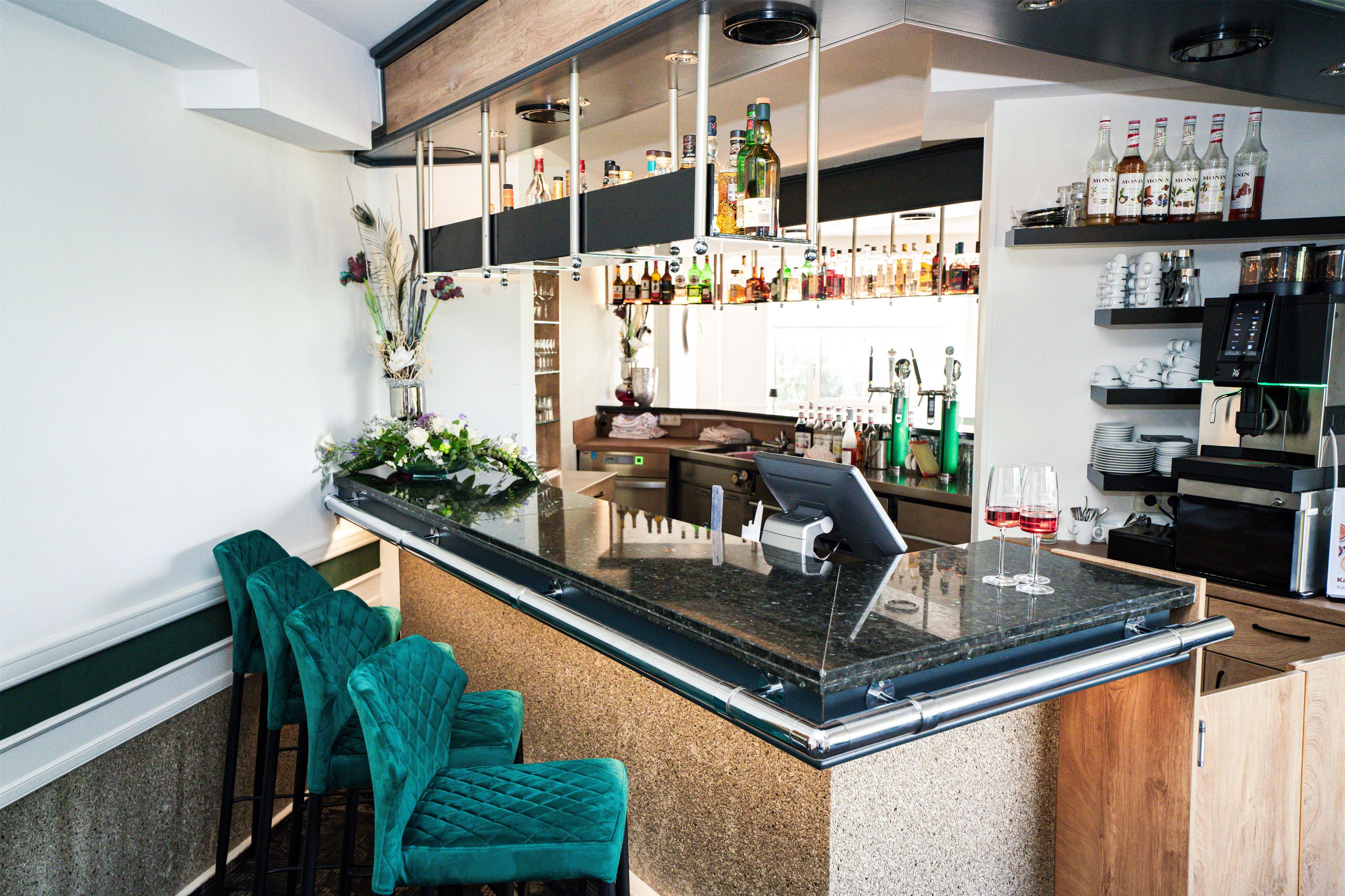 Eine Bar mit Theke, Sitzgelegenheiten und einer Auswahl an Flaschen.