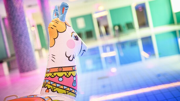 A colorful llama sculpture in a brightly lit indoor space with a tiled floor and green walls. - Holiday Inn Luebeck by IHG (Lübeck)