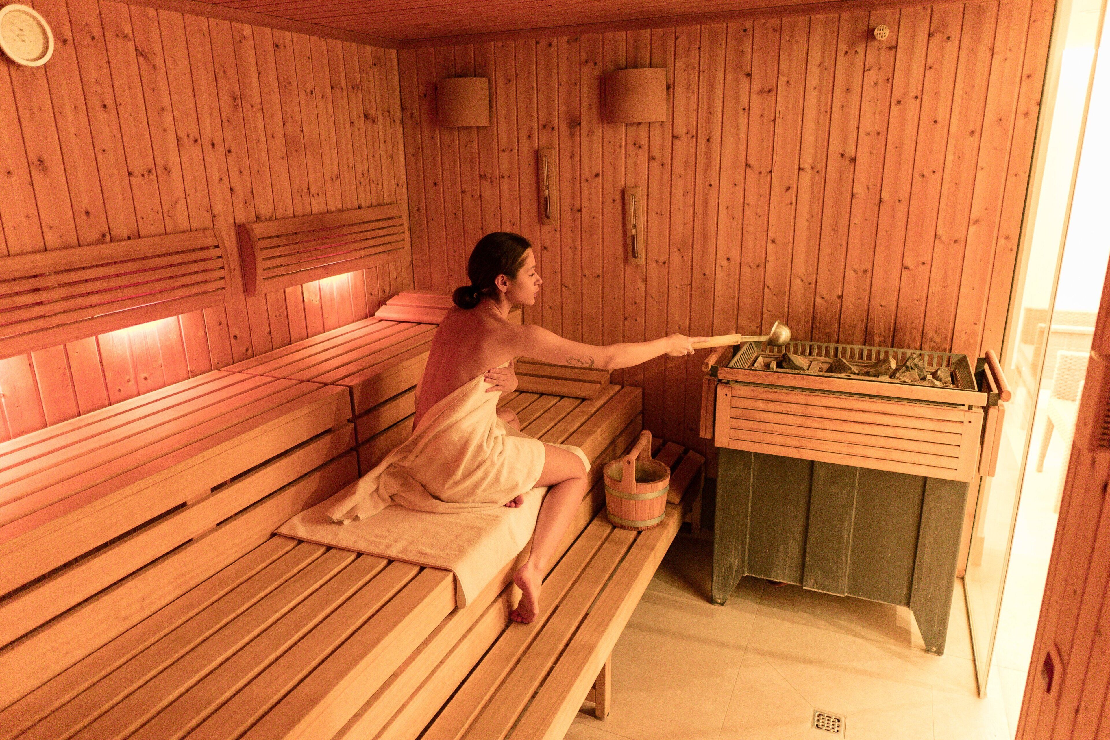 Un espai sauna de fusta amb seients i una taula de fusta amb un cubet.