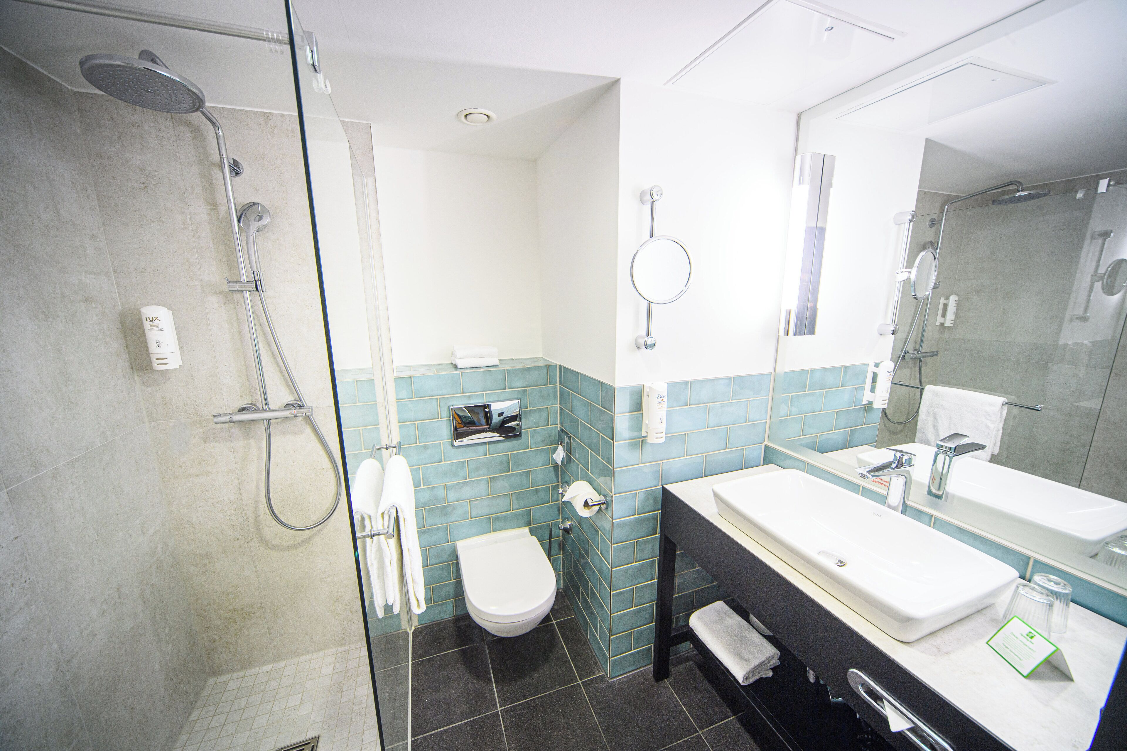 Un baño con ducha acristalada, inodoro, lavabo y espejo.