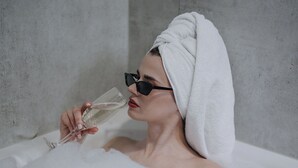 A person in a bathtub with a towel wrapped around their head, holding a glass. - Holiday Inn Luebeck by IHG (Lübeck)