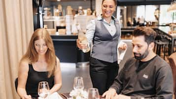 Un restaurante con un camarero sirviendo una botella de champán a una pareja sentada.