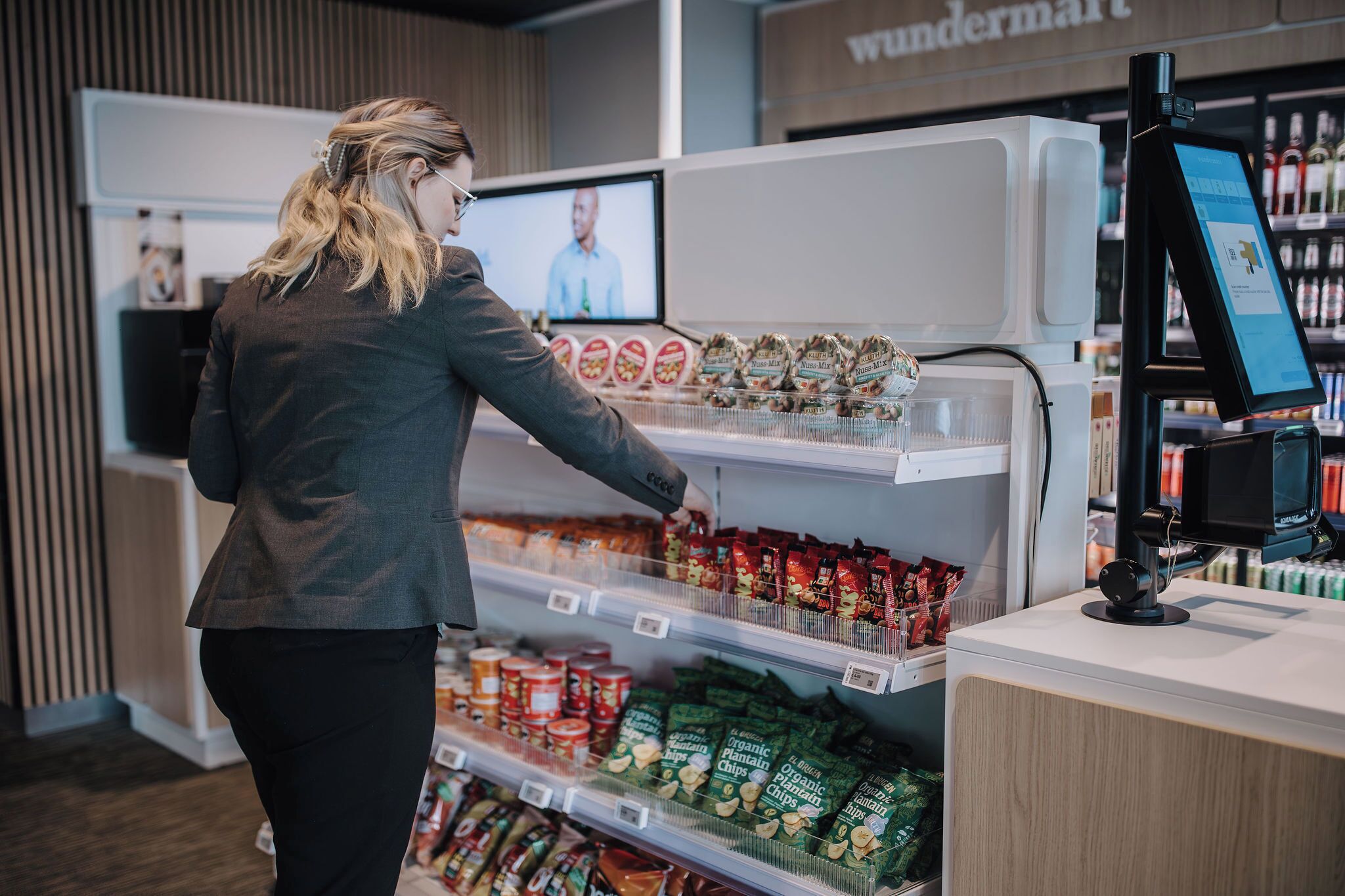 A person in a store selecting products from a refrigerated section.