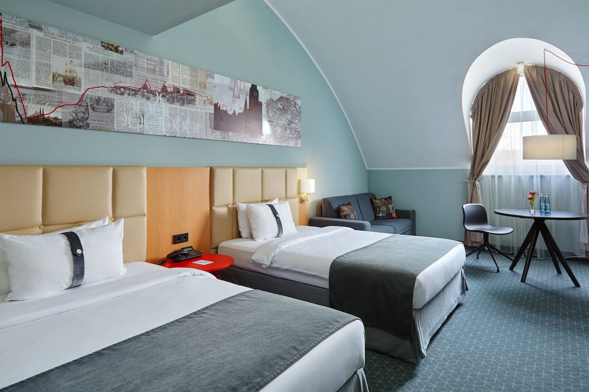 Quarto de hotel com duas camas, uma mesa de escritório, uma cadeira, uma mesa e um mapa grande na parede.