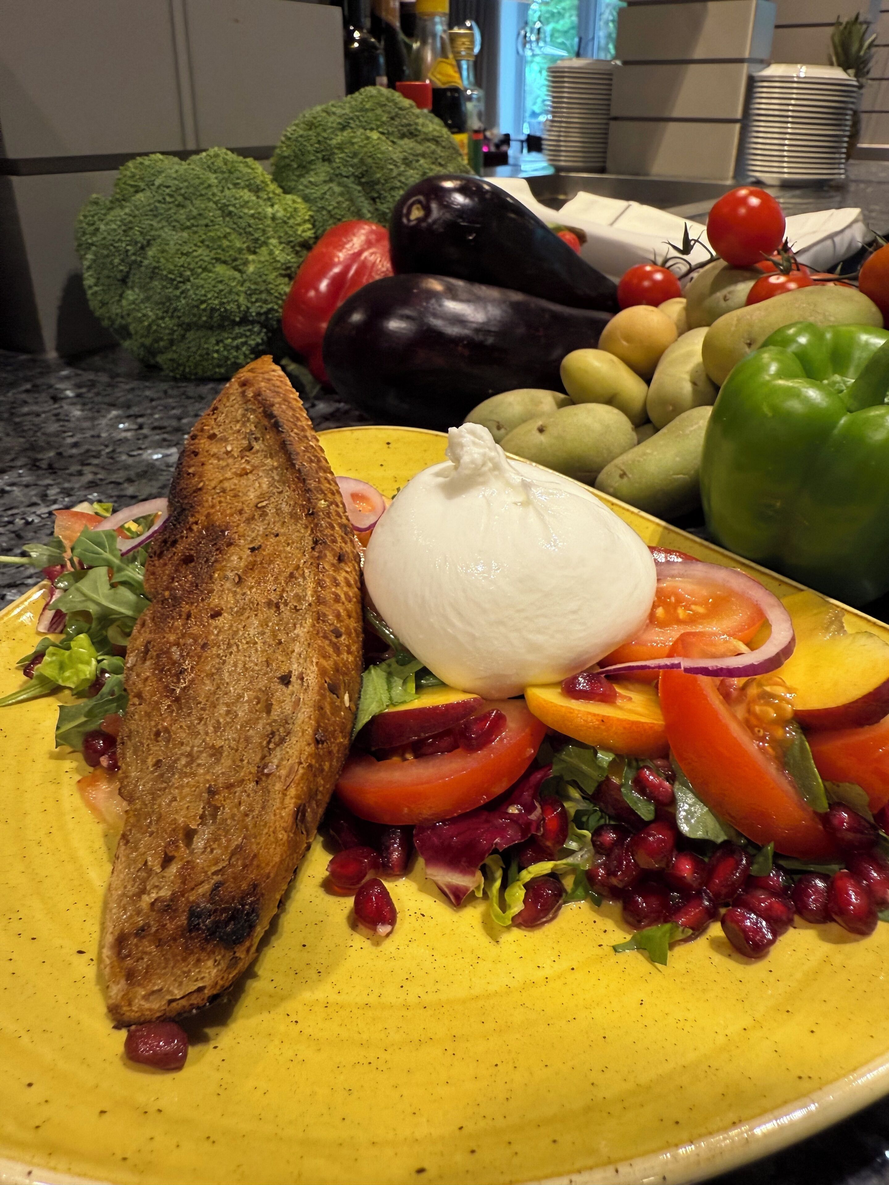 A plate of food with a variety of vegetables and a piece of bread.