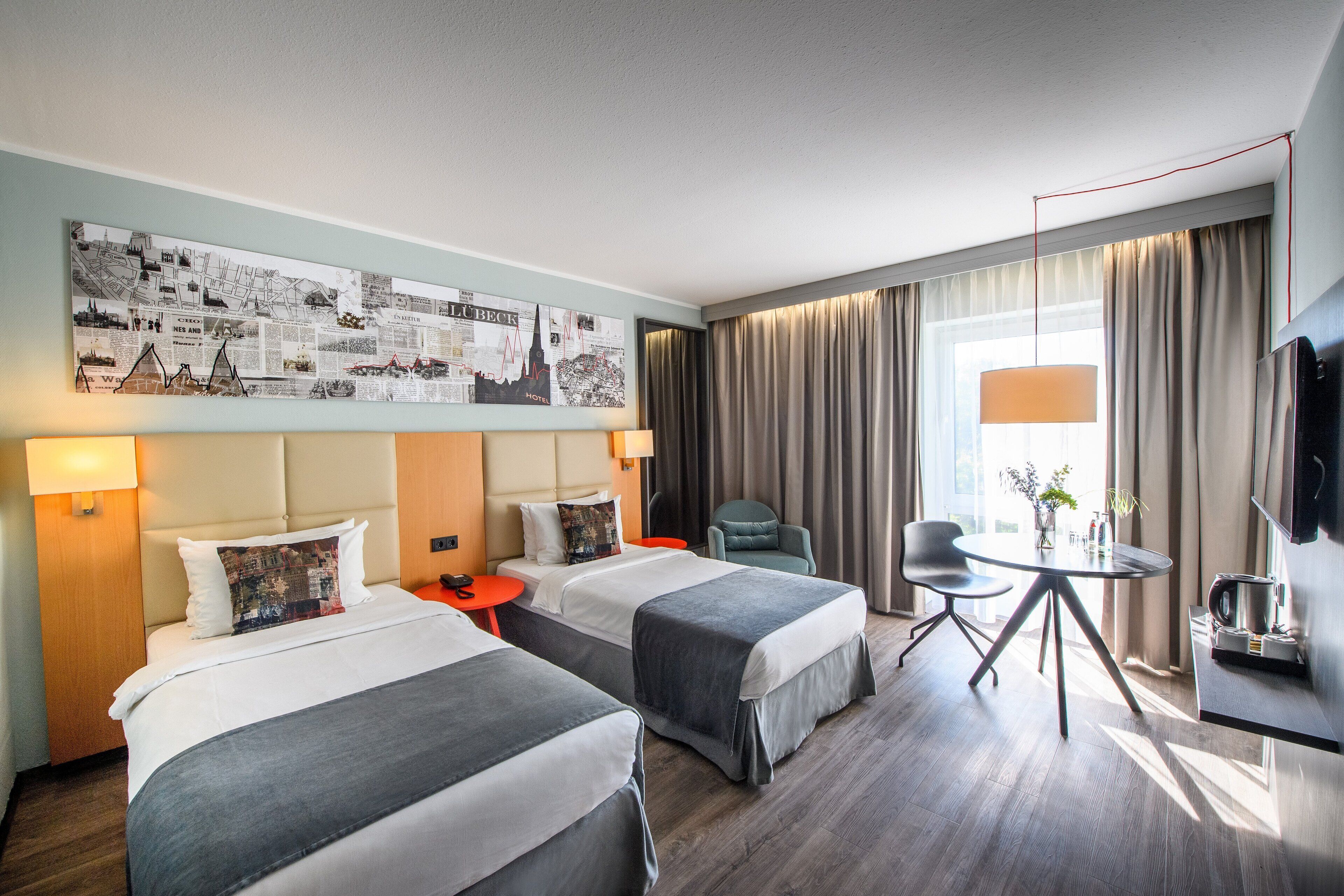 A hotel room with two beds, a desk, a chair, a TV, and a large cityscape artwork on the wall.