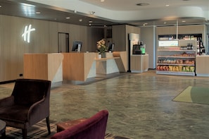 Welcome to our hotel lobby, featuring a reception desk, comfortable seating areas and a self-service kiosk.