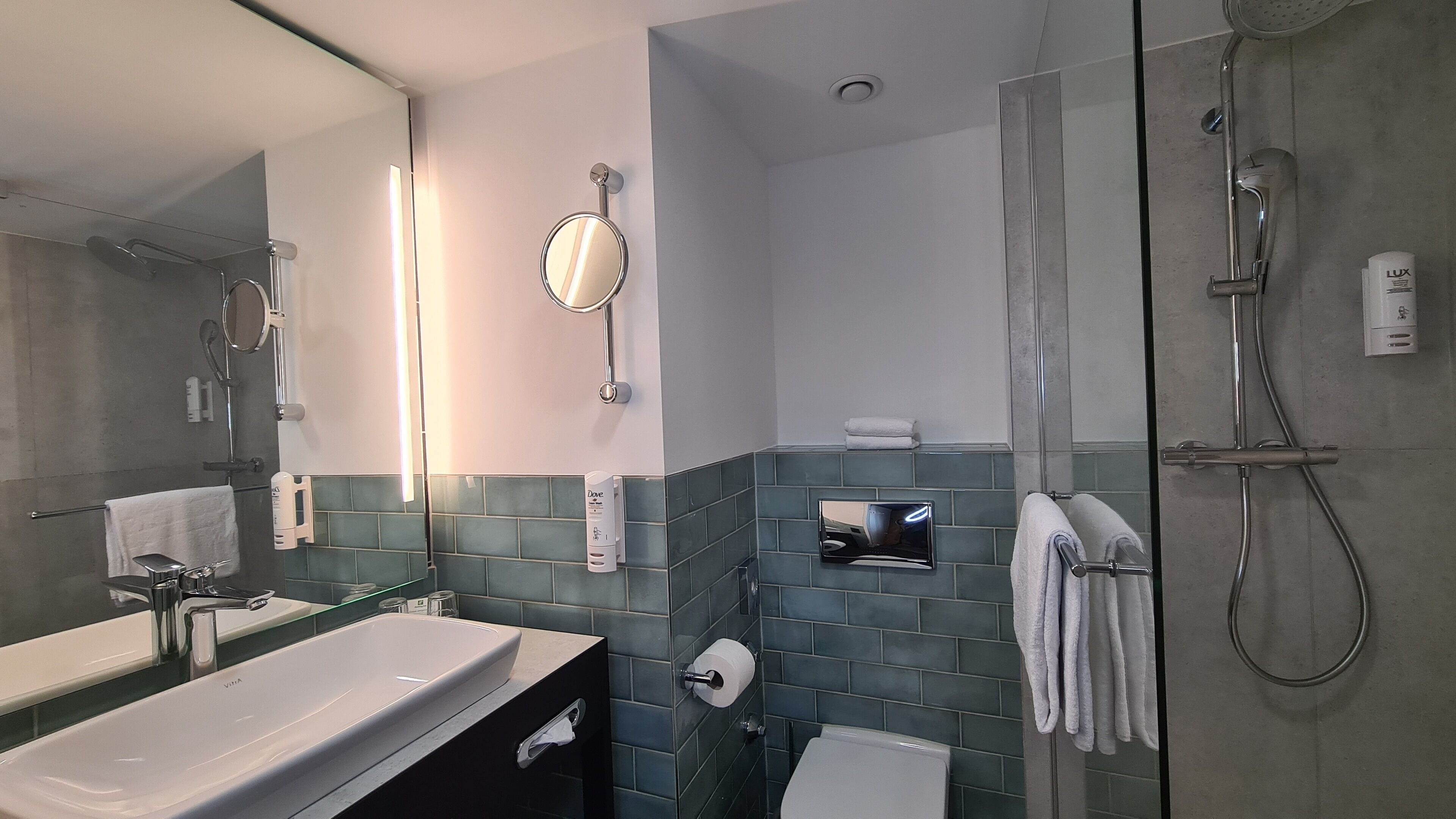 Ein modernes Badezimmer mit Duschkabine aus Glas, Waschbecken mit Spiegel und Toilette.