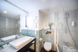 Features a dual sink vanity, glass-enclosed shower, and separate toilet.