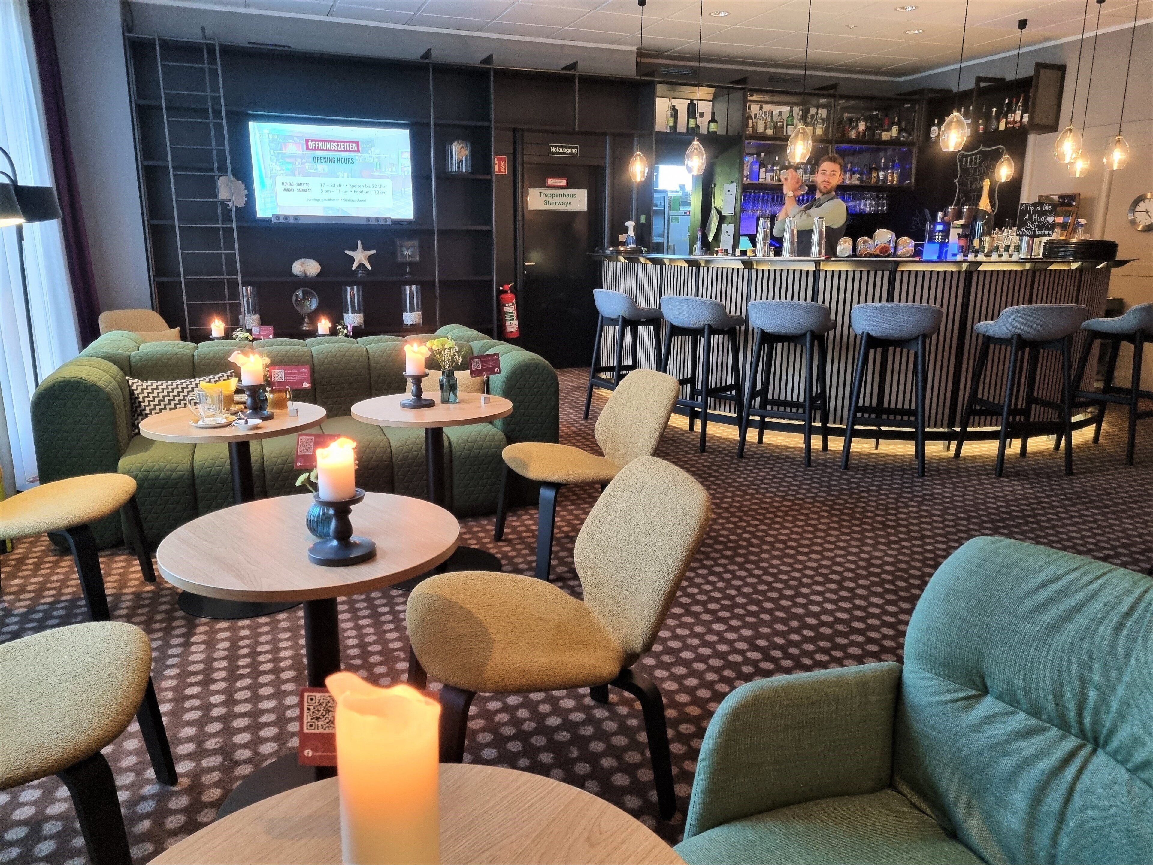 A bar area with stools, a counter, and a screen displaying opening hours.
