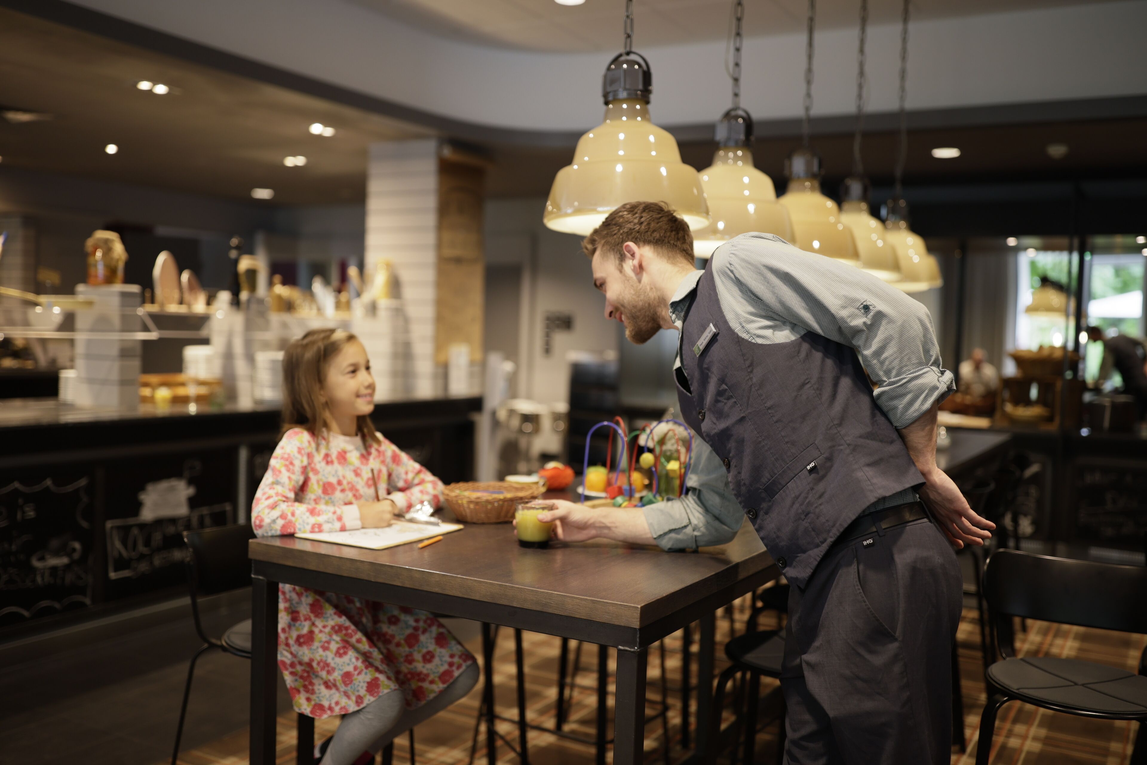 Un interior moderno con una zona de bar, iluminación colgante y una barra que exhibe diversos artículos.