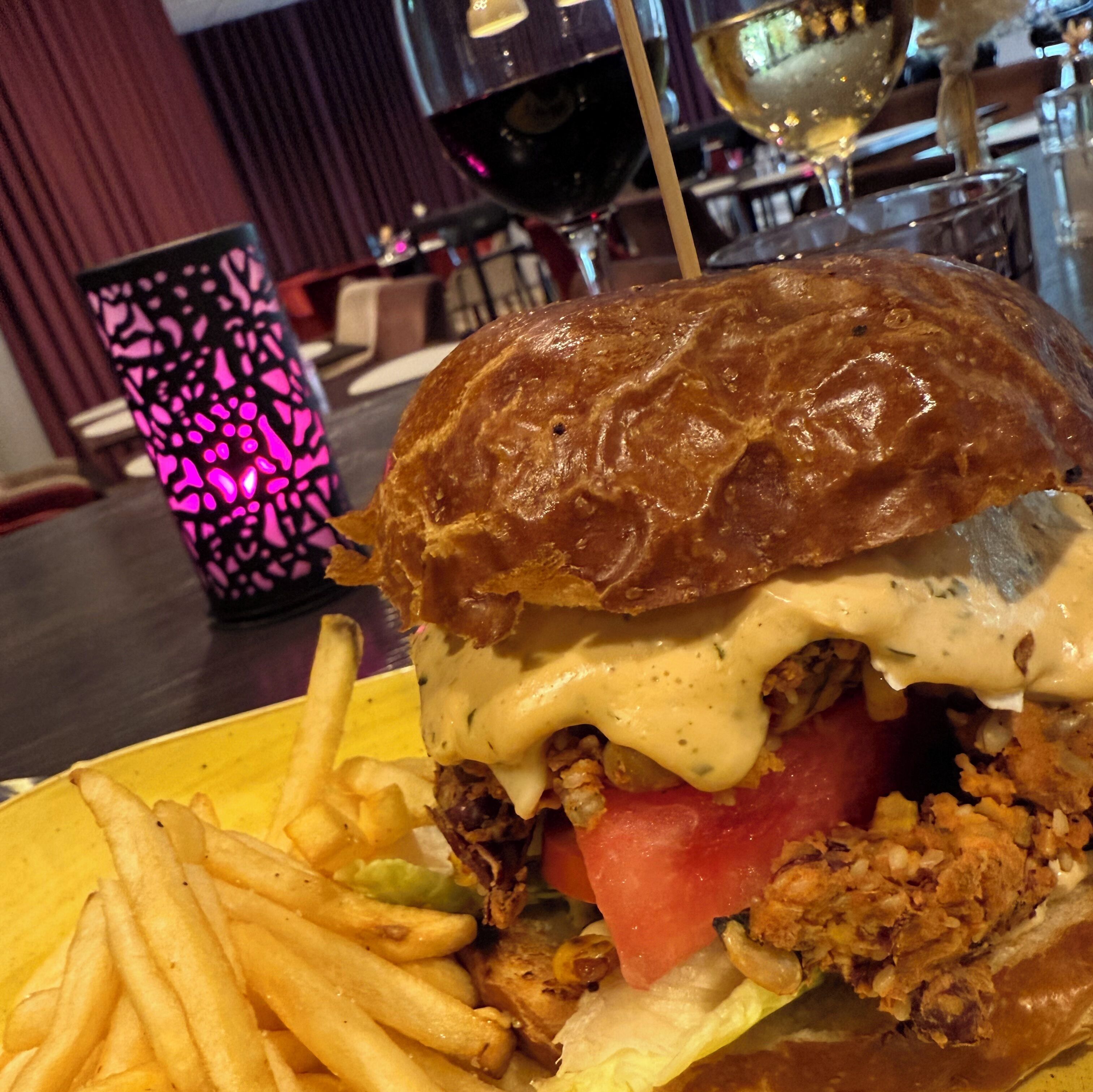 A close-up of a burger with fries on a yellow plate.