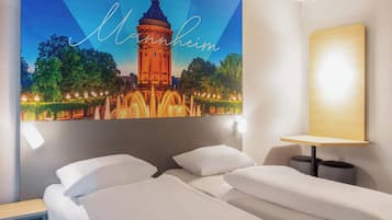 Habitación de hotel con cama, mesita de noche, lámpara de pared y un cuadro con una torre.
