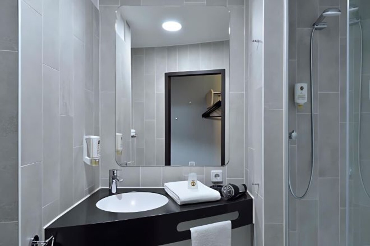 Un baño moderno con encimera negra, lavabo blanco y un espejo grande.