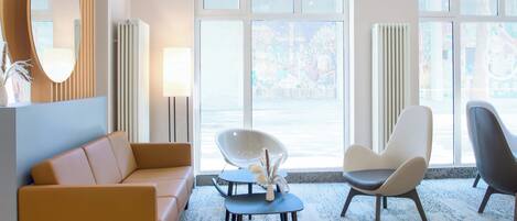 A modern room with a sofa, two chairs, a table, and a large window with a view.